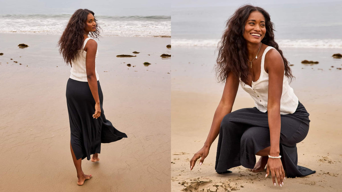 Image of woman on the beach wearing white tank and black skirt.