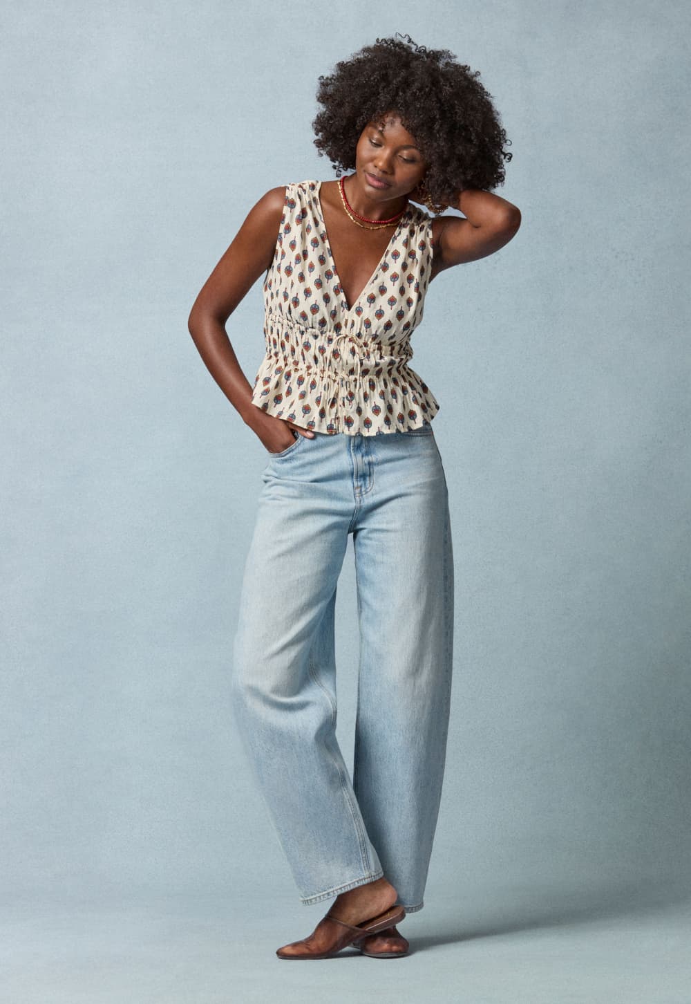 Image of woman wearing a printed tank with blue barrel cut jeans.