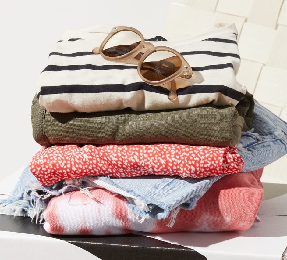 Image of a stack of folded EVEREVE clothes with sunglasses on top
