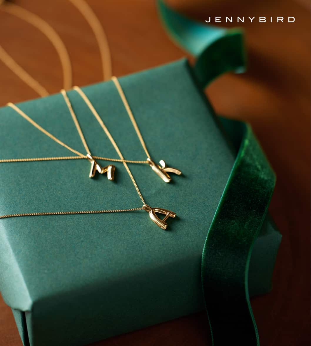 Image of an assortment of JENNYBIRD initial neckaces on a gift box with logo "JENNYBIRD"