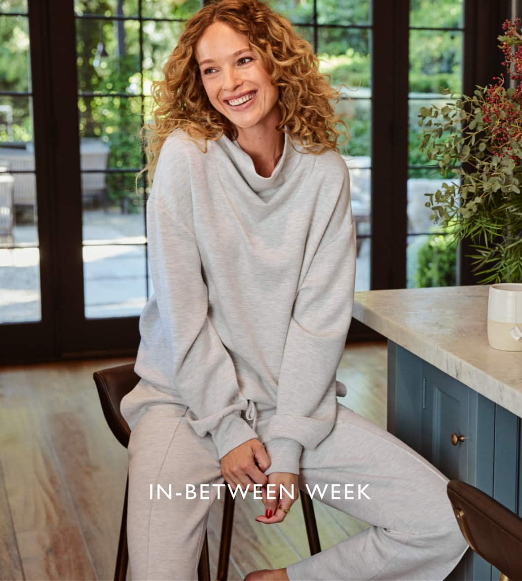 Image of a woman in cozy gray sweatshirt and sweatpants enjoying coffee in her kitchen with the copy "In-Between Week"