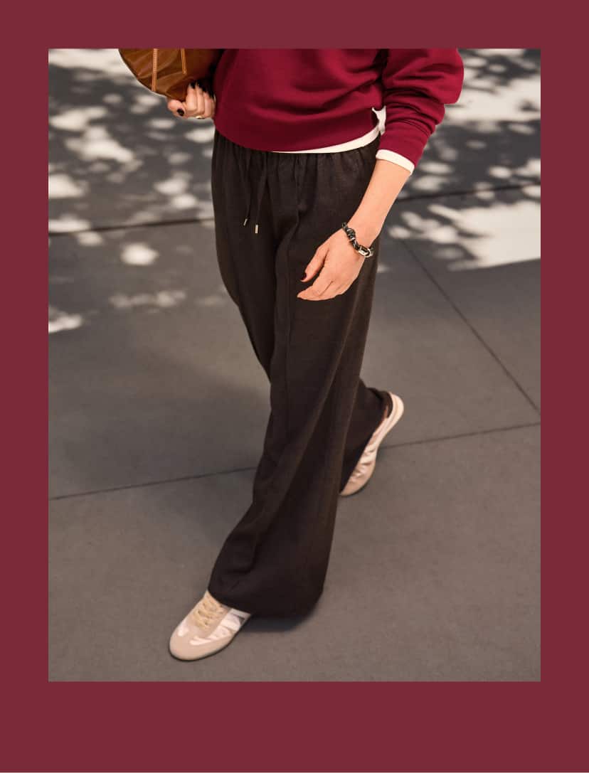 Woman wearing maroon pullover sweatshirt with bandana scarf and grey pull on track pants with sneakers.