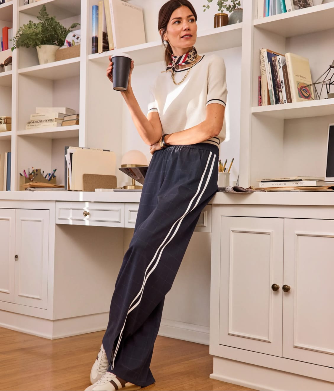 Woman wearing a white top with navy track pants and sneakers