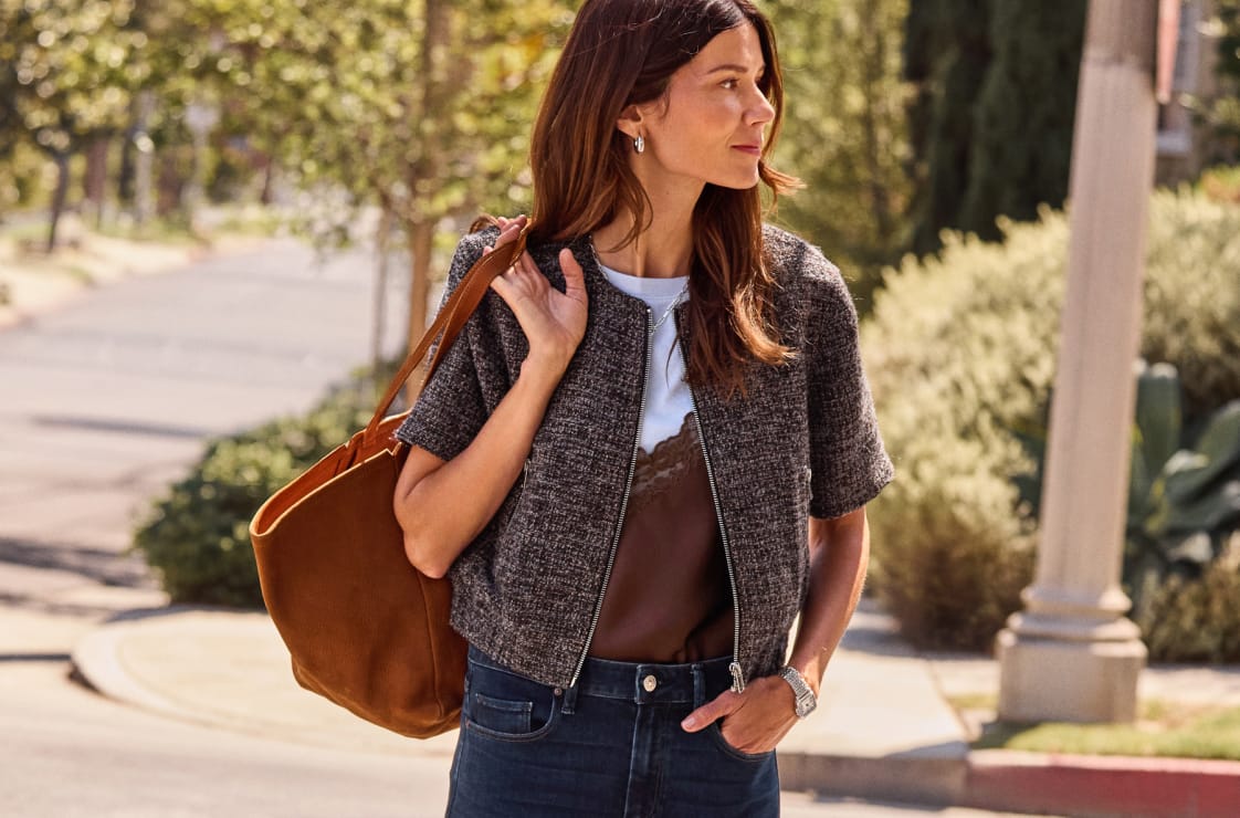 Woman wearing brown tweed short sleeve backet over a brown cami with blue jeans.