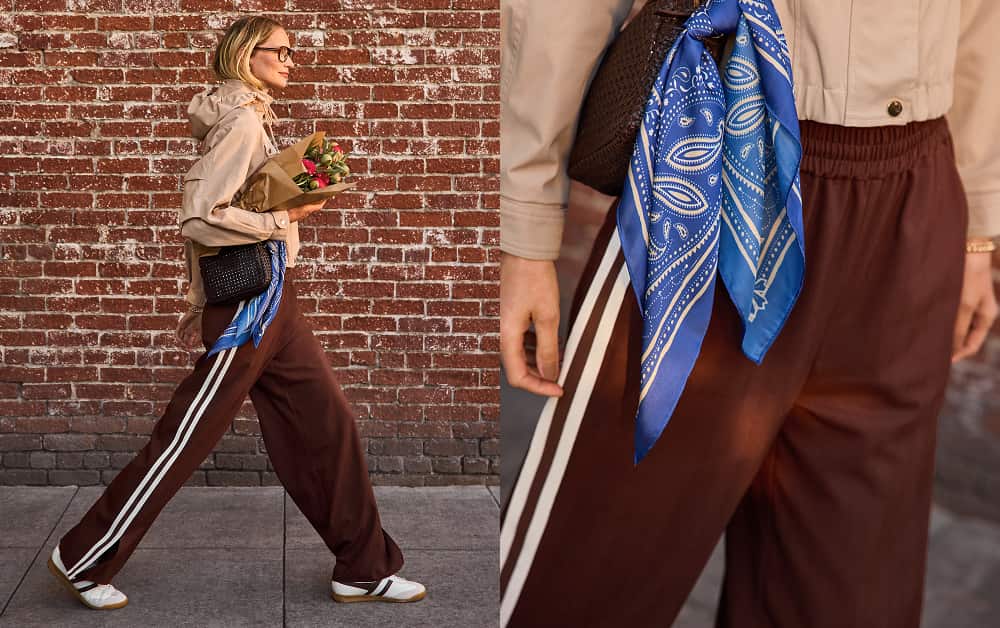 Woman wearing brown track pants with white side stripe and a blue scarf