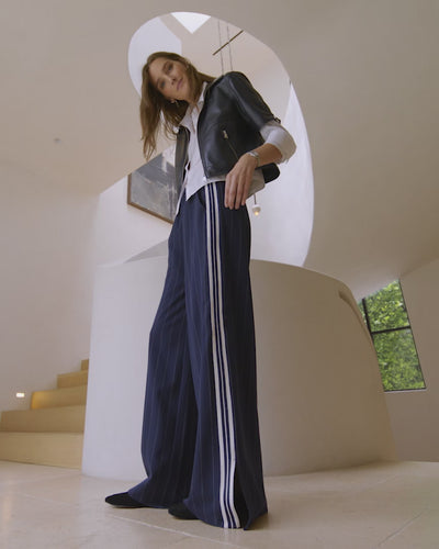 Video of woman wearing navy moto jacket with Tala track pants